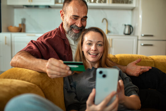 Smiling couple making mobile payment at home