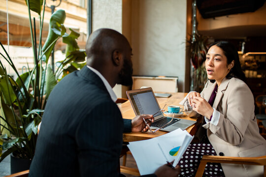 Two business professionals meeting at a cafe with laptop
