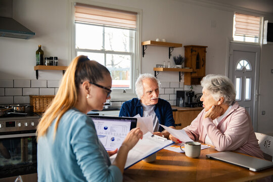 Financial advisor meeting with senior couple at home kitchen table
