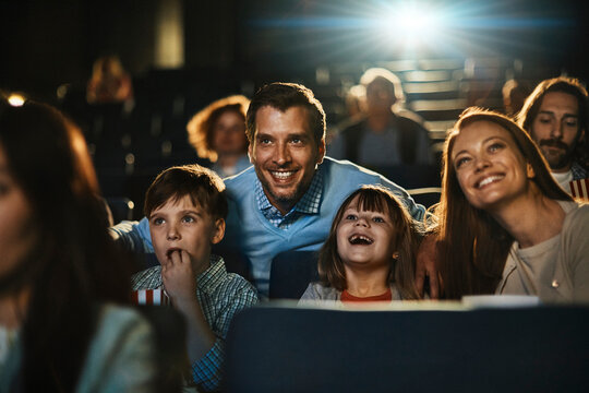Smiling family with kids watching a movie in cinema