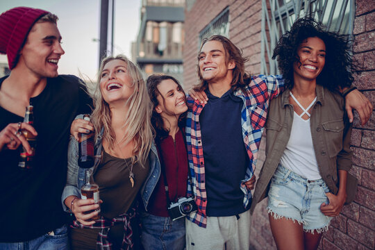 Group of friends laughing with drinks on a city street
