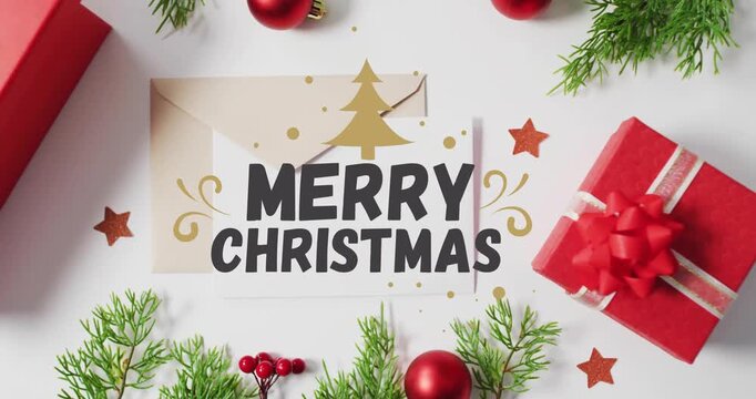Merry Christmas text animation over festive decorations with gifts and greenery