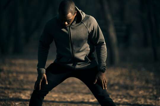 Man warming up in hoodie on forest trail