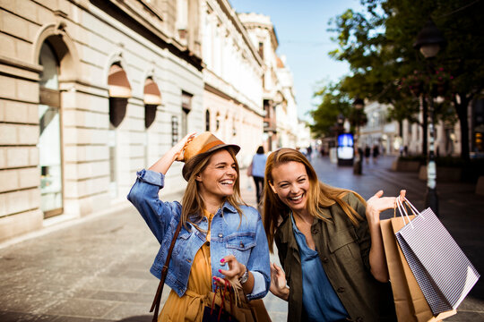 Two friends shopping and laughing on city street