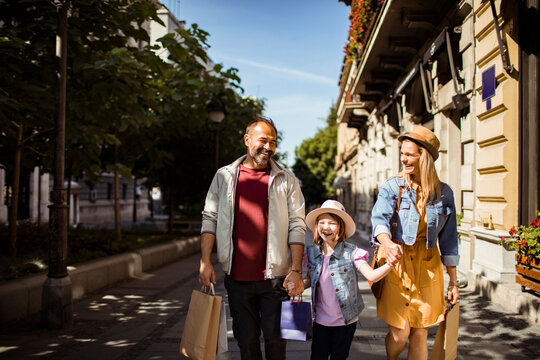 Smiling family shopping together on sunny city street