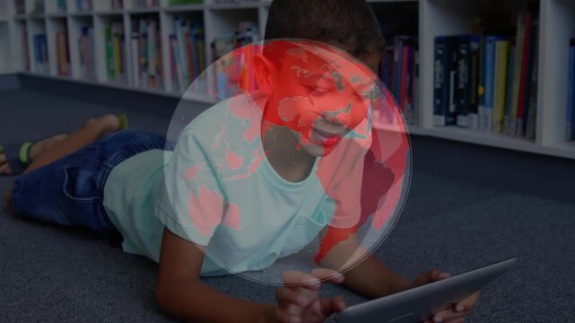 Boy lying in library tapping tablet as globe fading and rotating covering torso enabling education