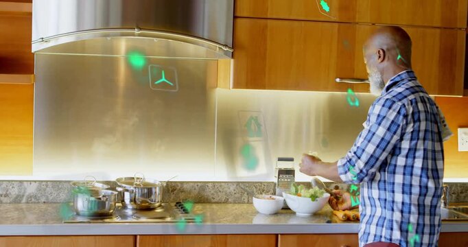 Green icons forming on backsplash responding to man seasoning salad, highlighting energy savings