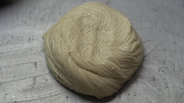 Close-up view of whole wheat dough leavening and expanding, showcasing the yeast fermentation process for homemade sourdough or brioche bread on a rustic kitchen surface