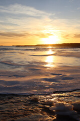 Obraz premium Frozen sea at sunset with golden light reflecting on ice