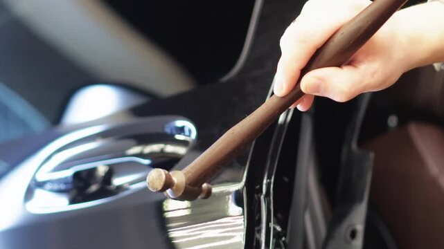 PDR. Process of paintless dent repair on car body. The mechanic at the auto shop with tools to repair dents in car body. Body repair. A specialist repairs a dent on the car body without painting. 