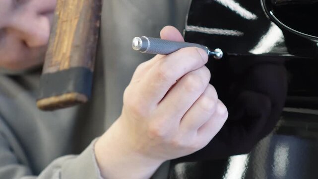 PDR. Process of paintless dent repair on car body. The mechanic at the auto shop with tools to repair dents in car body. Body repair. A specialist repairs a dent on the car body without painting. 