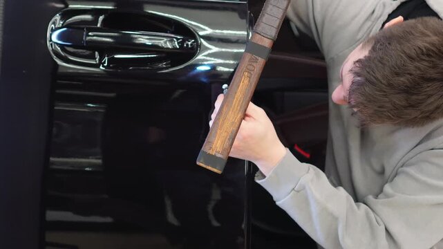 PDR. Process of paintless dent repair on car body. The mechanic at the auto shop with tools to repair dents in car body. Body repair. A specialist repairs a dent on the car body without painting. 