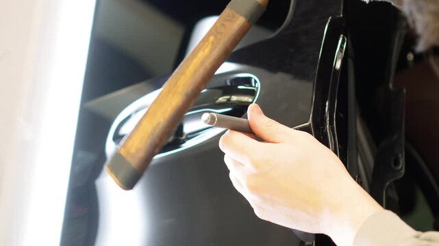 PDR. Process of paintless dent repair on car body. The mechanic at the auto shop with tools to repair dents in car body. Body repair. A specialist repairs a dent on the car body without painting. 
