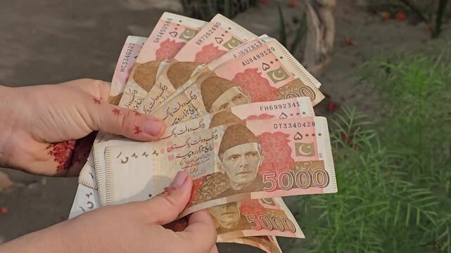 Five Thousands Pakistani bank currency notes displayed in a hand showcasing various denominations of pakistani rupee notes