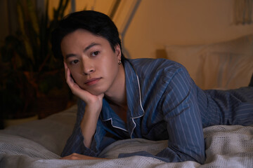 Obraz premium Asian man relaxing in his stylish modern apartment during nighttime hours