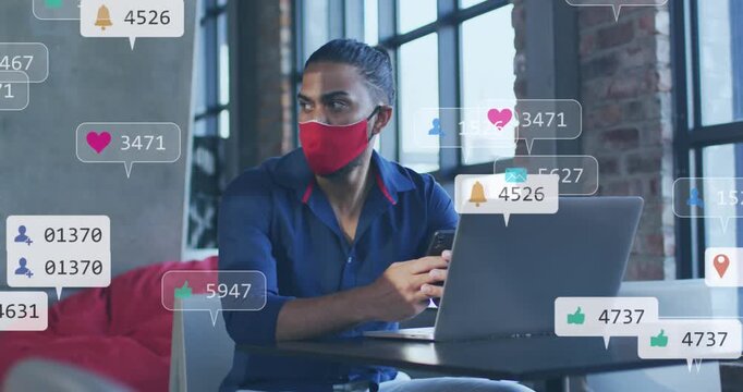 Animation of social media icons and numbers over businessman in face mask with laptop