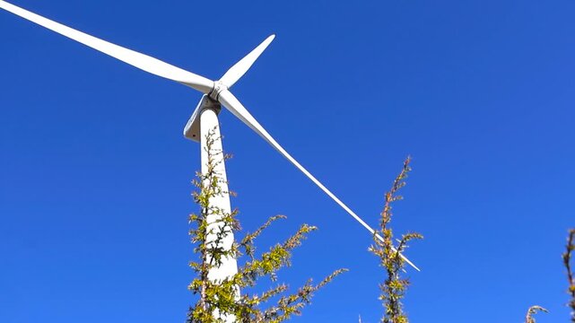 White wind turbine blades spinning with blue sky background