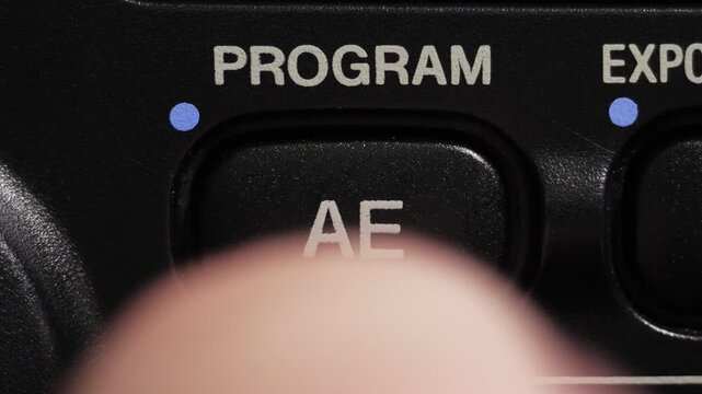 Macro close up of program AE button being pressed on camera control panel