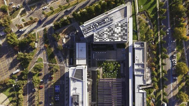 Top-down vertical drone shot ascending slowly over Universidad del Desarrollo geometric rooftop and central courtyard of a university building. Chile, 4K