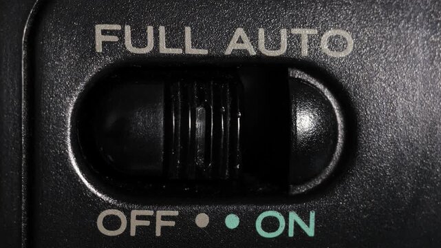 Macro close up of full auto switch sliding off to on, symbolizing automation and autopilot