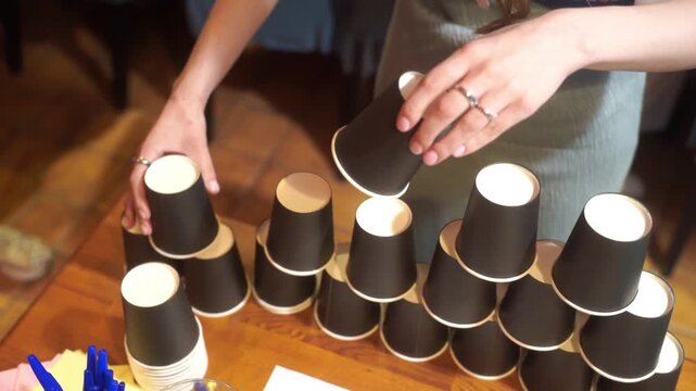 Pyramid of plastic cups on wooden table with green background. Party game