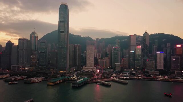 Breathtaking twilight panorama of Hong Kong's iconic skyline over Victoria Harbour. The red Hong Kong Observation Wheel glows in foreground with towering IFC skyscraper.