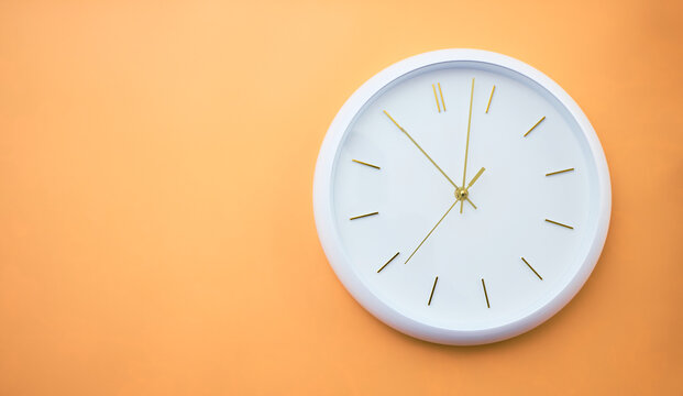 Minimalist white wall clock with gold hands on an orange background showing 1:53. Elegant modern design symbolizing time, precision, and contemporary aesthetics.