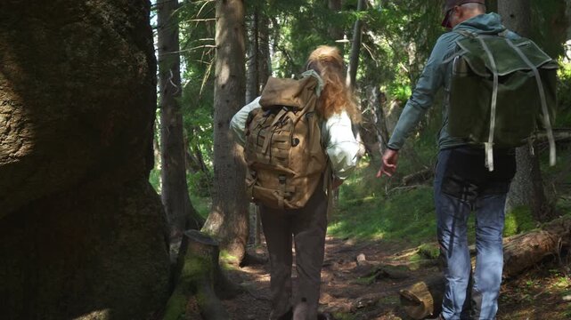 Couple hiking in Finnish forest, walking on a sunny trail among tall trees with backpacks in National Park, enjoying outdoor adventure and pure nature.