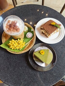 Indulge in a delightful cafe experience featuring a refreshing iced strawberry coffee, a classic tiramisu, and a vibrant matcha cheesecake. Perfect for a cozy afternoon treat or sharing with friends.