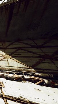 Workers inspect a damaged structure at a construction site. Pieces of wood and debris are scattered. The time of day appears to be late afternoon with shadows on the ground.