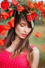 Naklejka premium A vertical close-up portrait of a beautiful young woman with long dark hair, wearing a red patterned dress and a large wreath of red poppies,