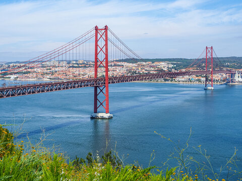 Over 2km-long, red Golden Gate-style, beautiful suspension bridge links Lisbon with Almada. Famous Ponte 25 de Abril bridge over the Tagus River. Panoramic view from Christ the King Square.