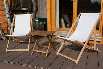 Relaxing outdoor seating with two white deck chairs and a wooden table