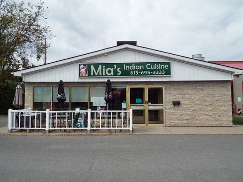 Ottawa, Ontario, Canada-July 23, 2025: The stone facade of "Mia&rsquo;s Indian Cuisine" features a small outdoor patio with tables and black umbrellas at 917 Richmond Rd.
