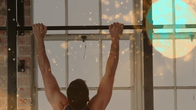 Man gripping pull-up bar and pulling up in loft windows, bokeh highlighting strength for fitness