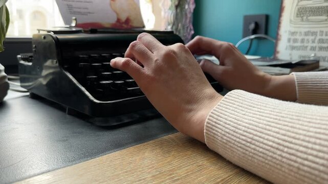 Minsk Belarus March 23 2026 Hands type on vintage typewriter on table in cafe interior. Fingers press keys on retro machine during writing process. Concept creativity, text, communication, old