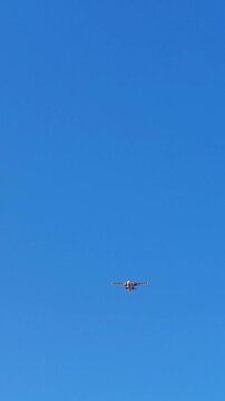 low angle view twin-engine propeller airplane soaring through cloudless, vibrant blue sky on sunny day, showcasing freedom flight and aviation travel. vertical.