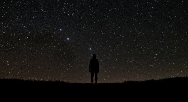Solitary silhouette stands beneath a brilliantly star-filled night sky