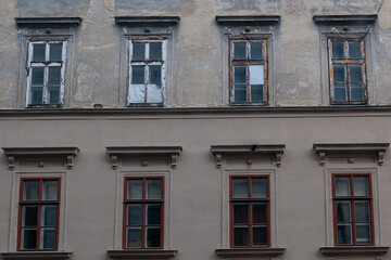 Old Building Facade With Weathered Windows and Rustic Architectural Details in Urban Setting © Olga