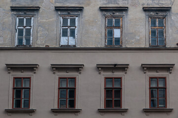 Old Building Facade With Weathered Windows and Rustic Architectural Details in Urban Setting © Olga