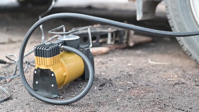 Equipment is placed on dirt, connected to a vehicle tire for inflation.