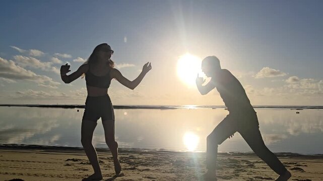 silhueta de casal jogando capoeira na praia 