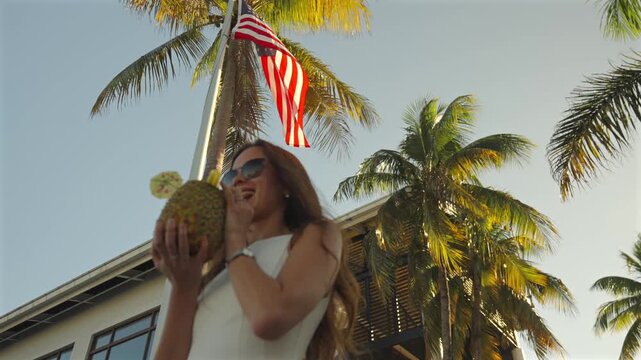 Smiling woman holding pineapple drink under palms Miami Florida USA