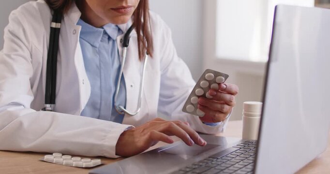 Doctor looking at tablets blister to check name and information online, medicine instruction for dosage. Woman holding pills by laptop to search for medical prescription details and side effects