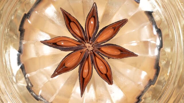 Artistic macro of star anise on glass bottom with light refraction. Creative radial pattern for abstract food design and culinary backgrounds.