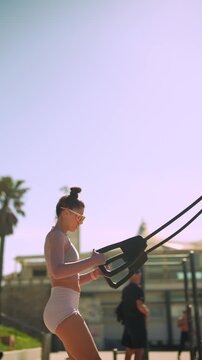 Side view of woman engaging core during resistance exercises by sea
