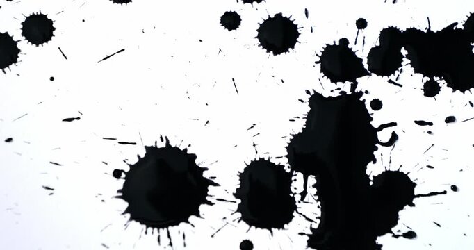 Black spots on a white background. Ink spills onto white paper. Black drops and white surface.
