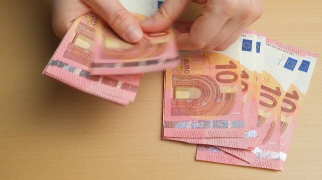Hands counting 10 euro banknotes on a table