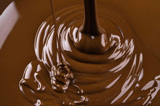 Ribbons hot chocolate pouring forming waves. stream of sweet syrup as background