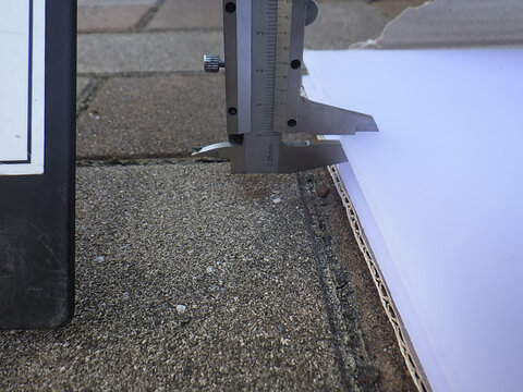 Measuring the thickness of a polycarbonate sheet with a vernier caliper for material inspection, Japan
